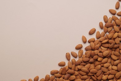 Photo of Delicious raw almonds on beige background, flat lay. Space for text