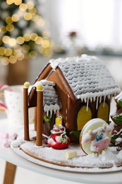 Beautiful gingerbread house decorated with icing on white table indoors