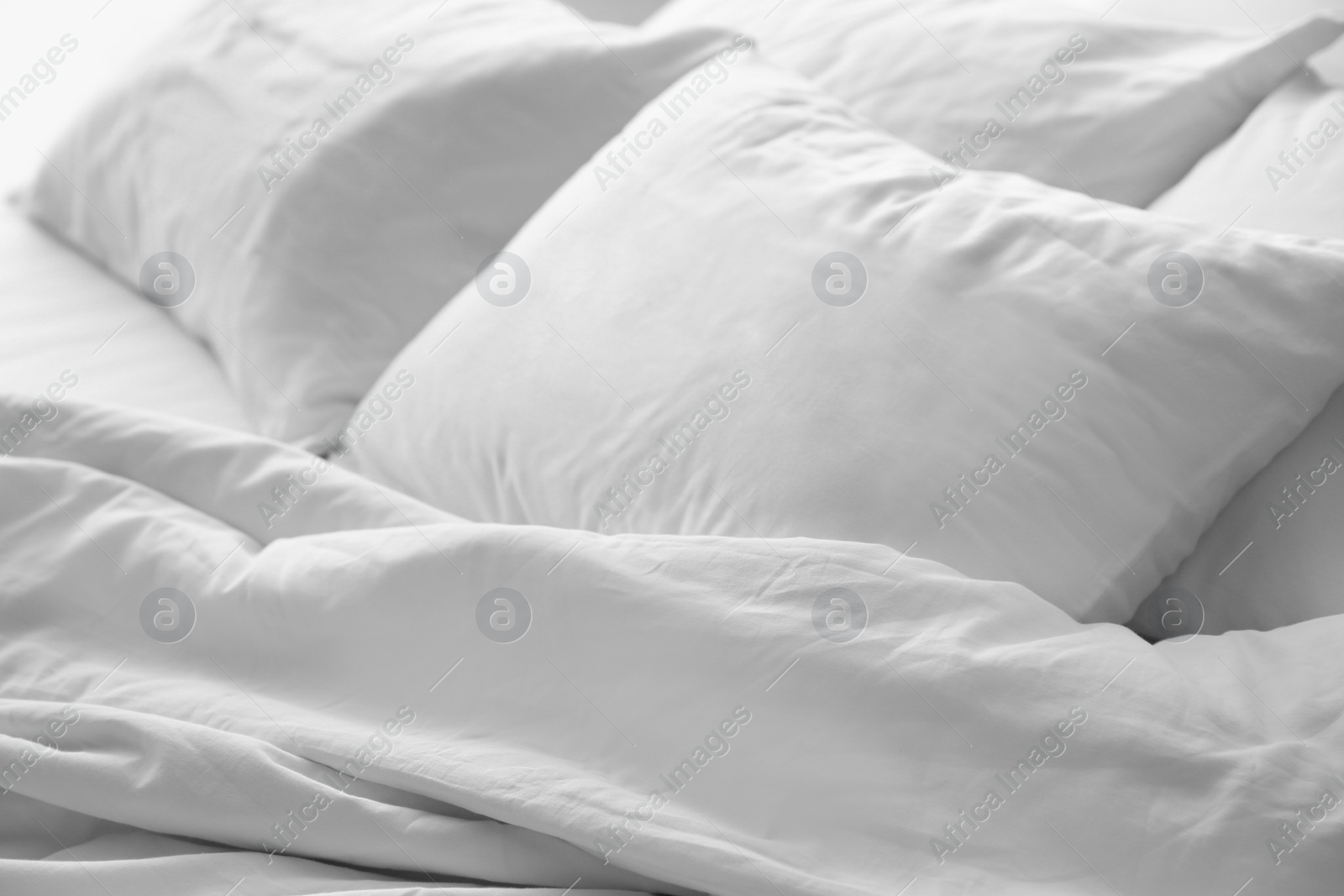 Photo of Soft white pillows on messy bed, closeup