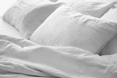 Soft white pillows on messy bed, closeup