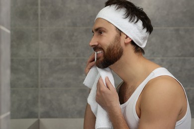 Photo of Washing face. Man with headband and towel in bathroom, space for text