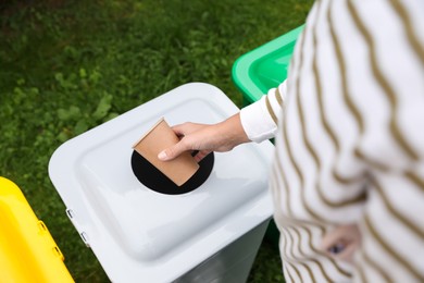Photo of Woman throwing coffee cup into recycling bin outdoors, closeup
