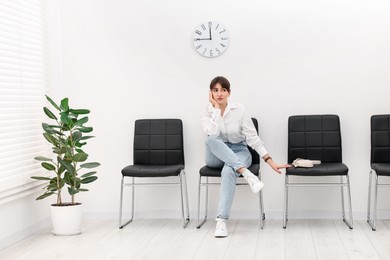 Photo of Woman sitting on chair and waiting for appointment indoors