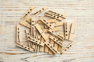 Photo of Pile of clothes pins on white wooden table, flat lay