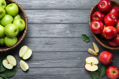 Juicy red apples in wicker baskets on grey wooden table, flat lay. Space for text