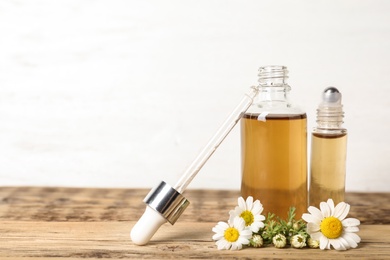 Photo of Composition with bottles of chamomile essential oil on table. Space for text