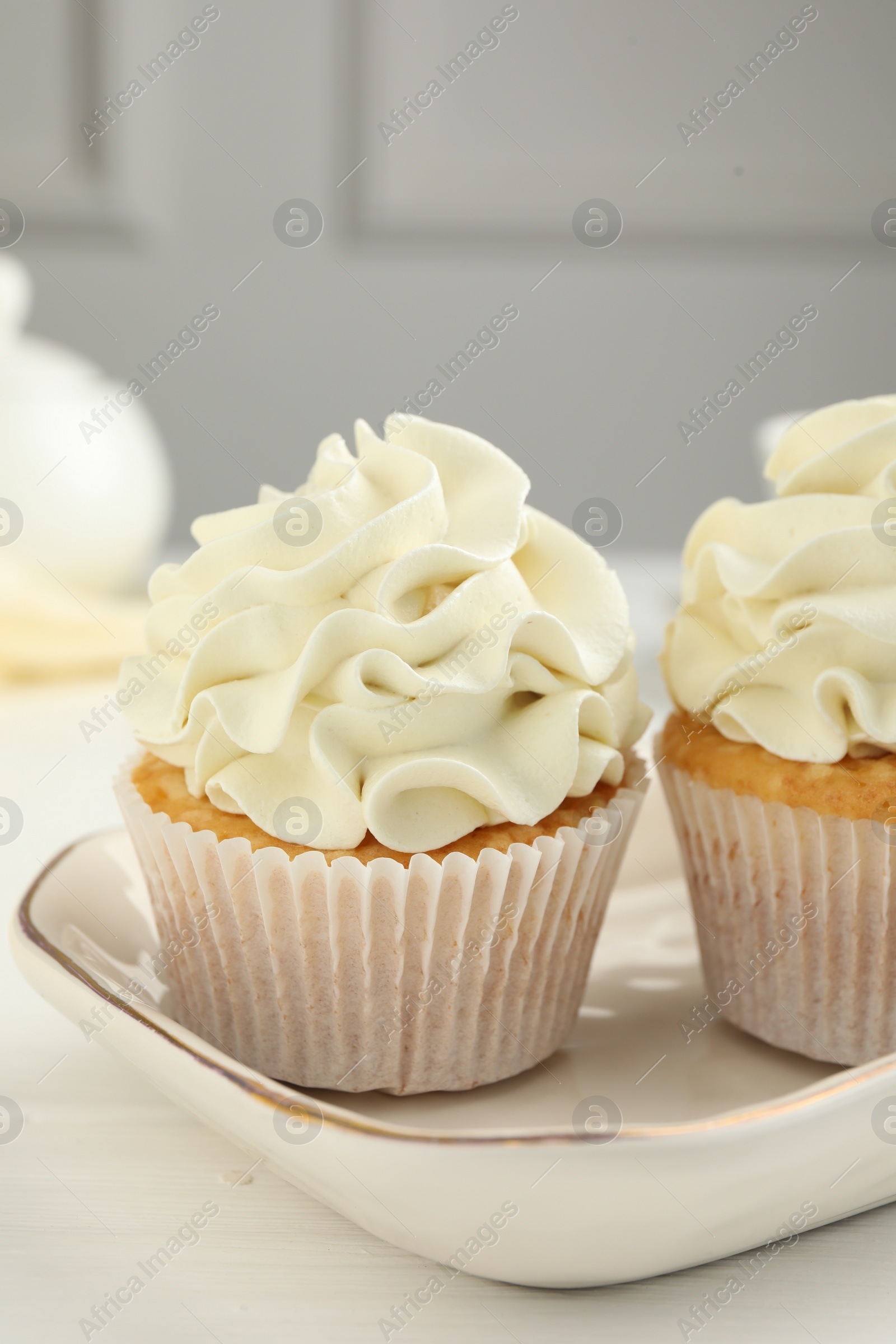 Photo of Tasty cupcakes with vanilla cream on white wooden table, closeup