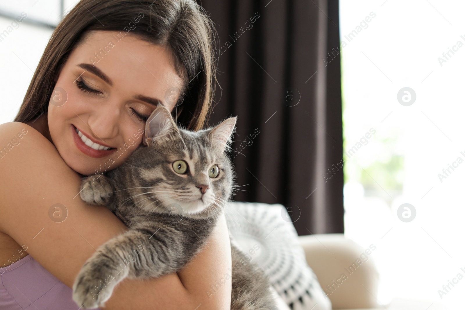 Photo of Young woman with cute cat at home, space for text. Pet and owner