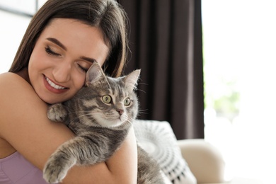 Photo of Young woman with cute cat at home, space for text. Pet and owner