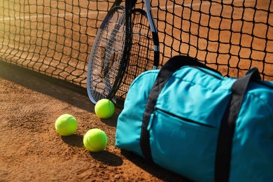 Tennis balls, rackets and bag near net on clay court