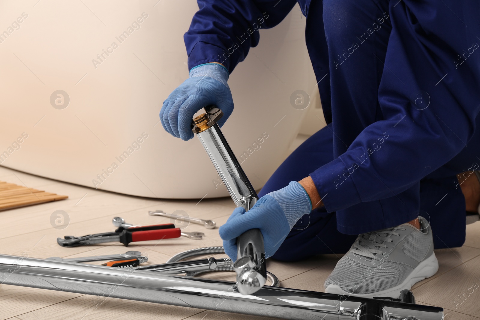 Photo of Professional plumber installing water tap in bathroom, closeup