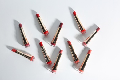 Photo of Set of bright lipsticks in gold tubes on white background, flat lay