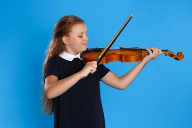 Photo of Preteen girl playing violin on light blue background