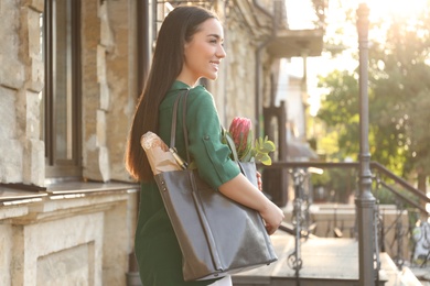 Photo of Young woman with leather shopper bag near building