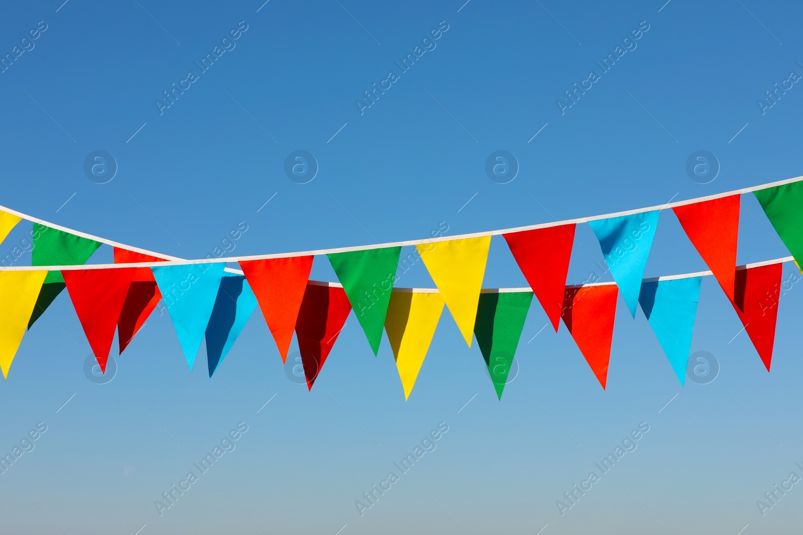 Photo of Buntings with colorful triangular flags against blue sky