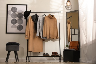 Stylish warm clothes on rack in dressing room interior
