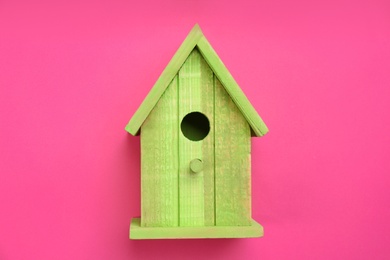Beautiful bird house on pink background, top view