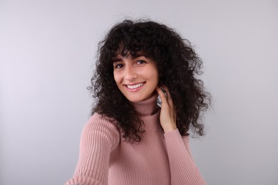 Beautiful young woman taking selfie on light grey background