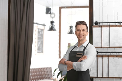 Photo of Young waiter in apron at workplace