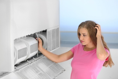 Young woman fixing air conditioner at home