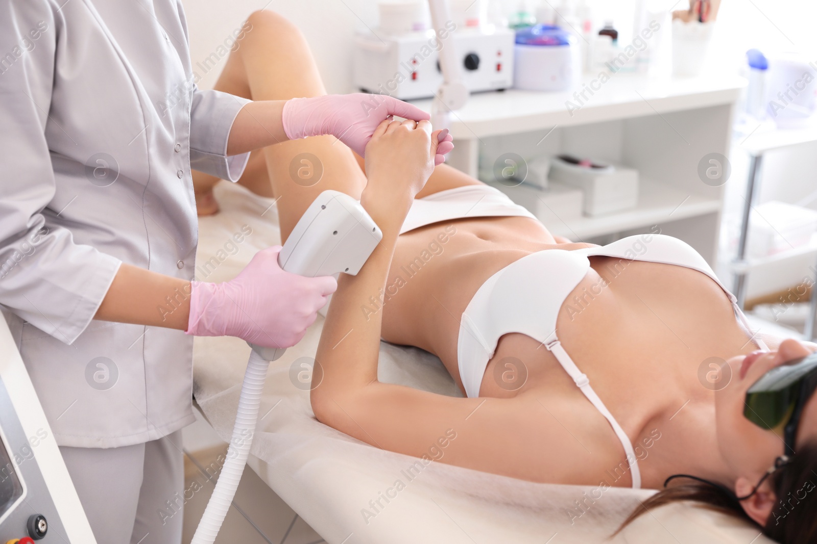 Photo of Young woman undergoing laser epilation procedure in beauty salon, closeup