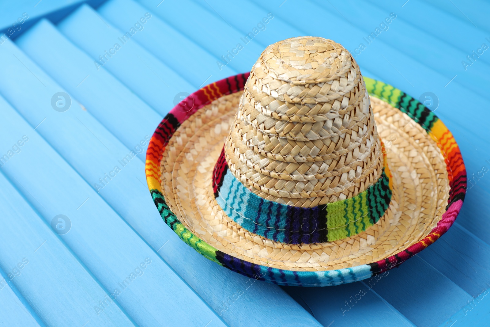 Photo of Mexican sombrero hat on blue wooden surface. Space for text