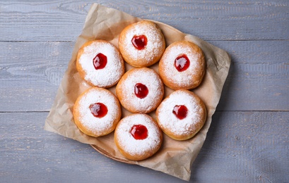 Photo of Hanukkah doughnuts with jelly and sugar powder on grey wooden table, top view