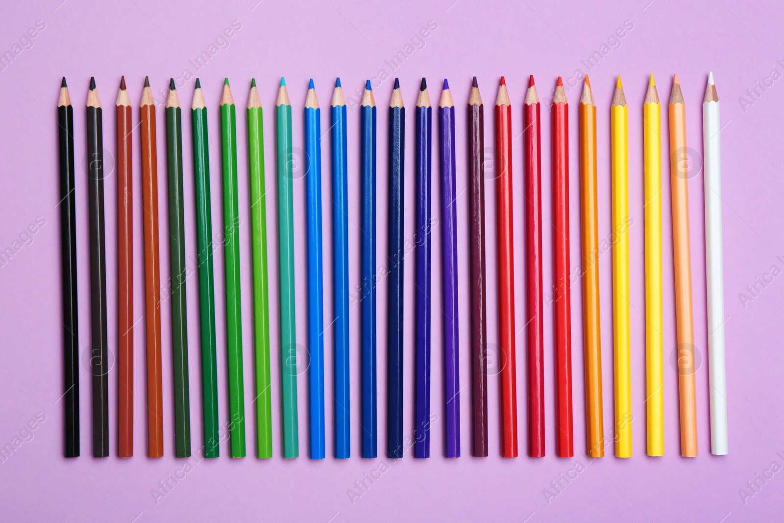 Photo of Color pencils on lilac background, flat lay