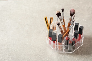 Lipstick holder with different makeup products on grey background. Space for text