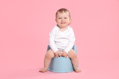 Photo of Little child sitting on baby potty against pink background