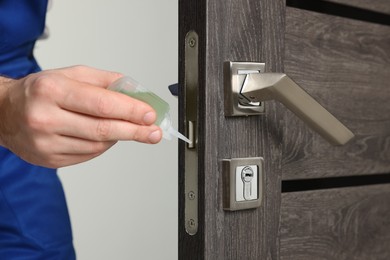 Worker lubricating door lock indoors, closeup view