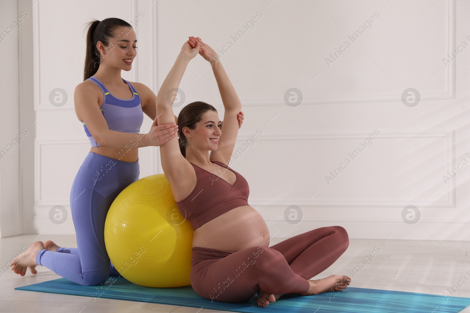 Photo of Trainer working with pregnant woman in gym. Preparation for child birth