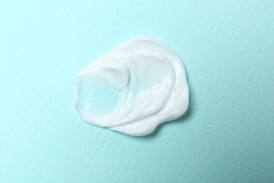 Photo of Sample of hand cream on turquoise background, top view