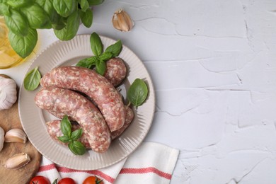 Raw homemade sausages and different products on white textured table, flat lay. Space for text