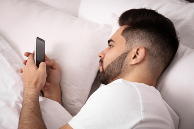 Photo of Young man addicted to smartphone in bed at home