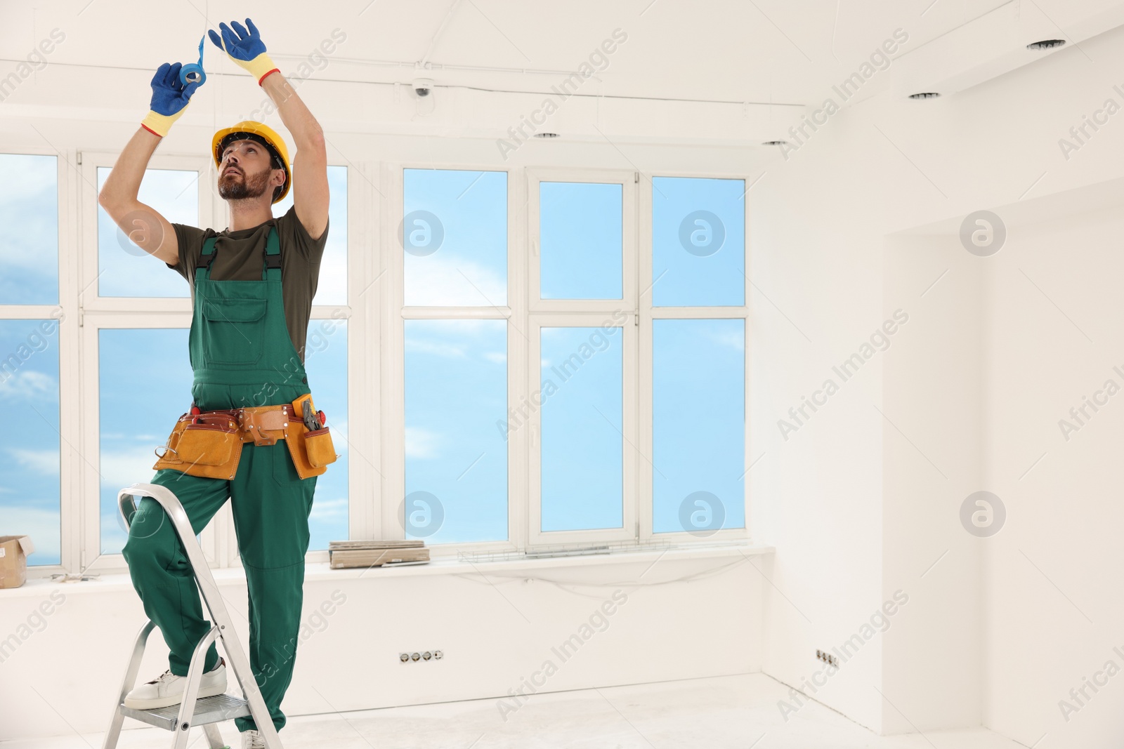 Photo of Electrician fixing wires with insulating tape indoors