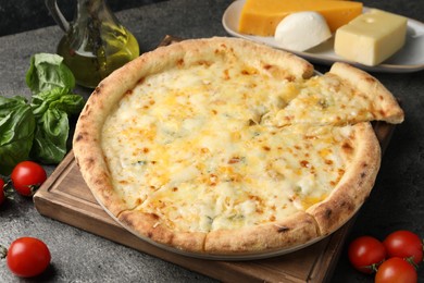 Delicious cheese pizza and ingredients on dark grey table