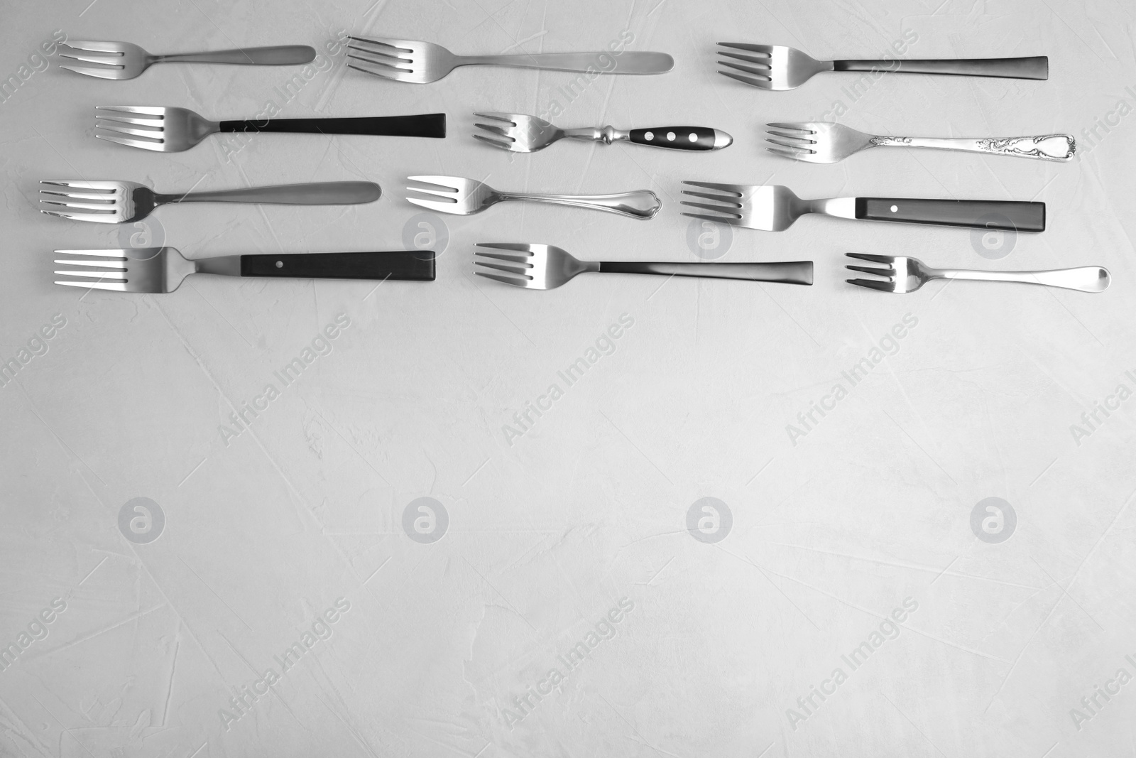 Photo of Flat lay composition with different forks on grey table, space for text