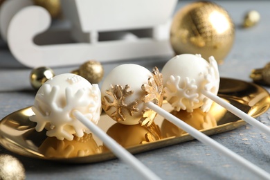 Photo of Delicious Christmas themed cake pops on golden plate, closeup