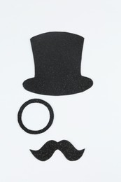 Photo of Fake mustache, hat and monocle on light background, top view