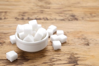 White sugar cubes on wooden table, space for text