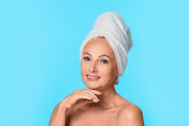 Portrait of beautiful mature woman with perfect skin on light blue background