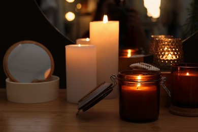 Photo of Lit candles on wooden dressing table indoors