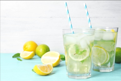 Photo of Glasses of refreshing lemonade on light blue table, space for text. Summer drink