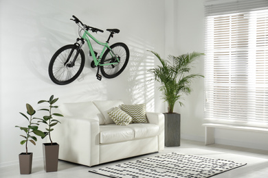 Photo of Stylish living room interior with white sofa and green bicycle