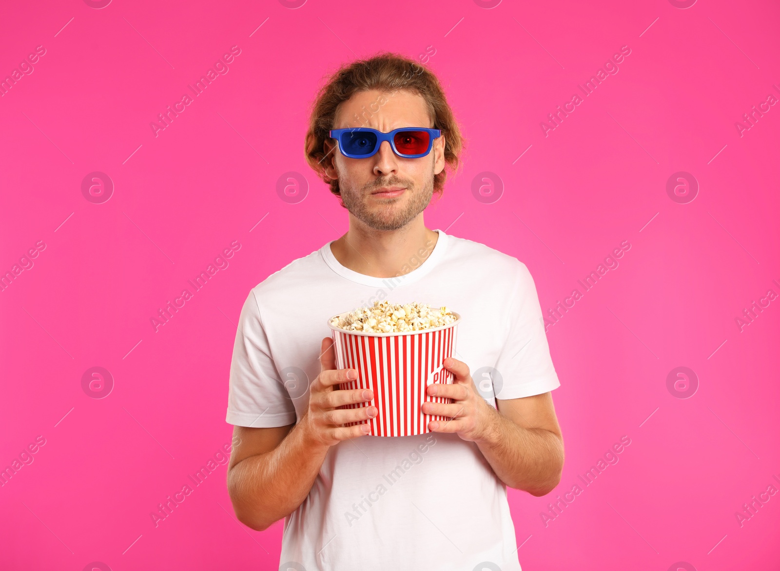 Photo of Emotional man with 3D glasses and popcorn during cinema show on color background