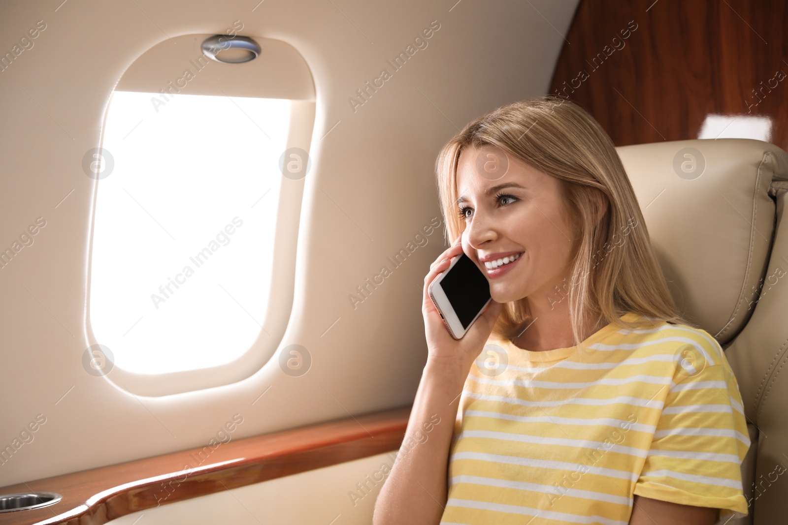 Photo of Young woman talking on phone before flight in plane