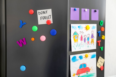 Photo of Modern refrigerator with child's drawings, notes and magnets, closeup