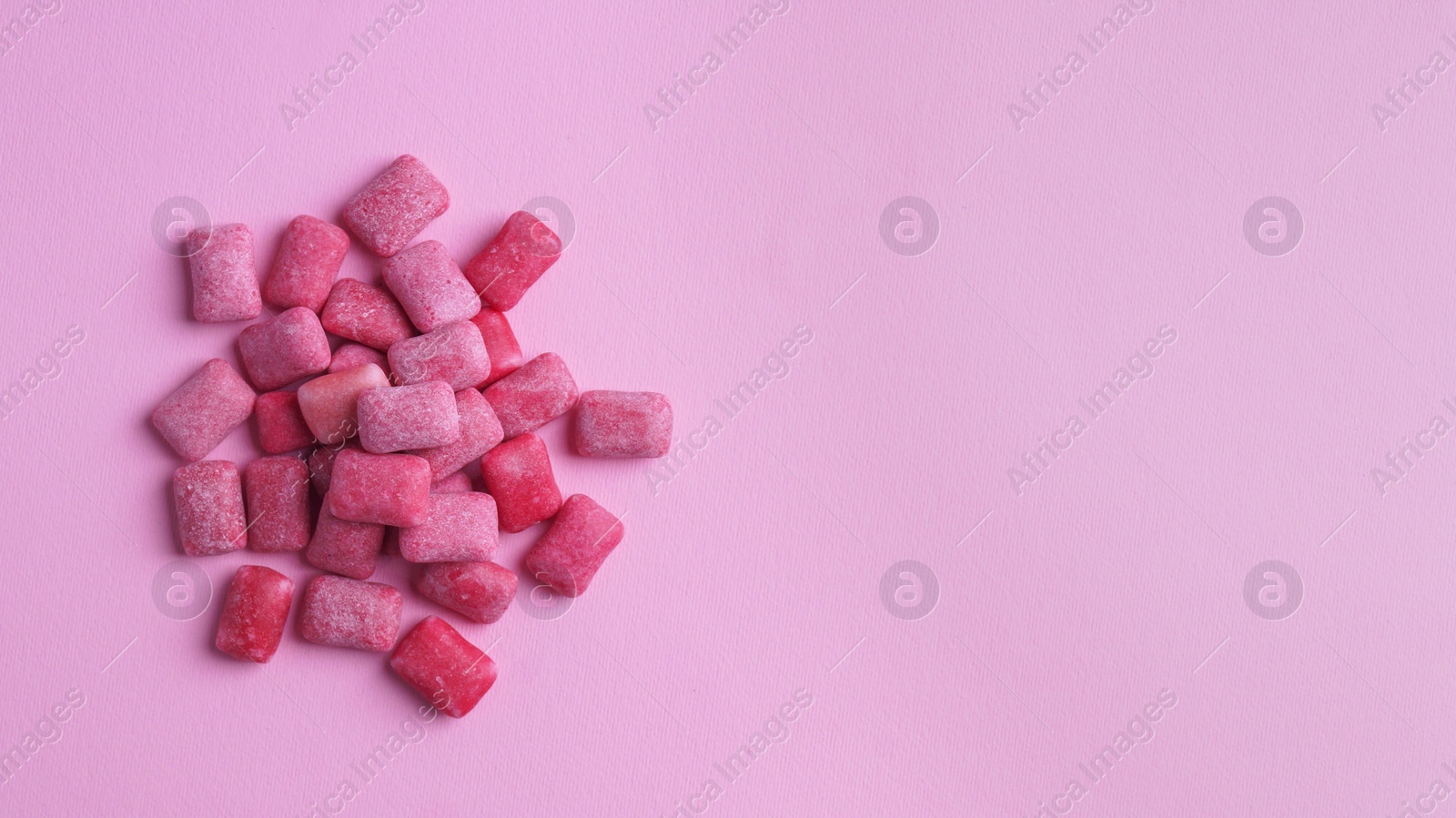 Photo of Heap of tasty sweet chewing gums on pink background, flat lay. Space for text