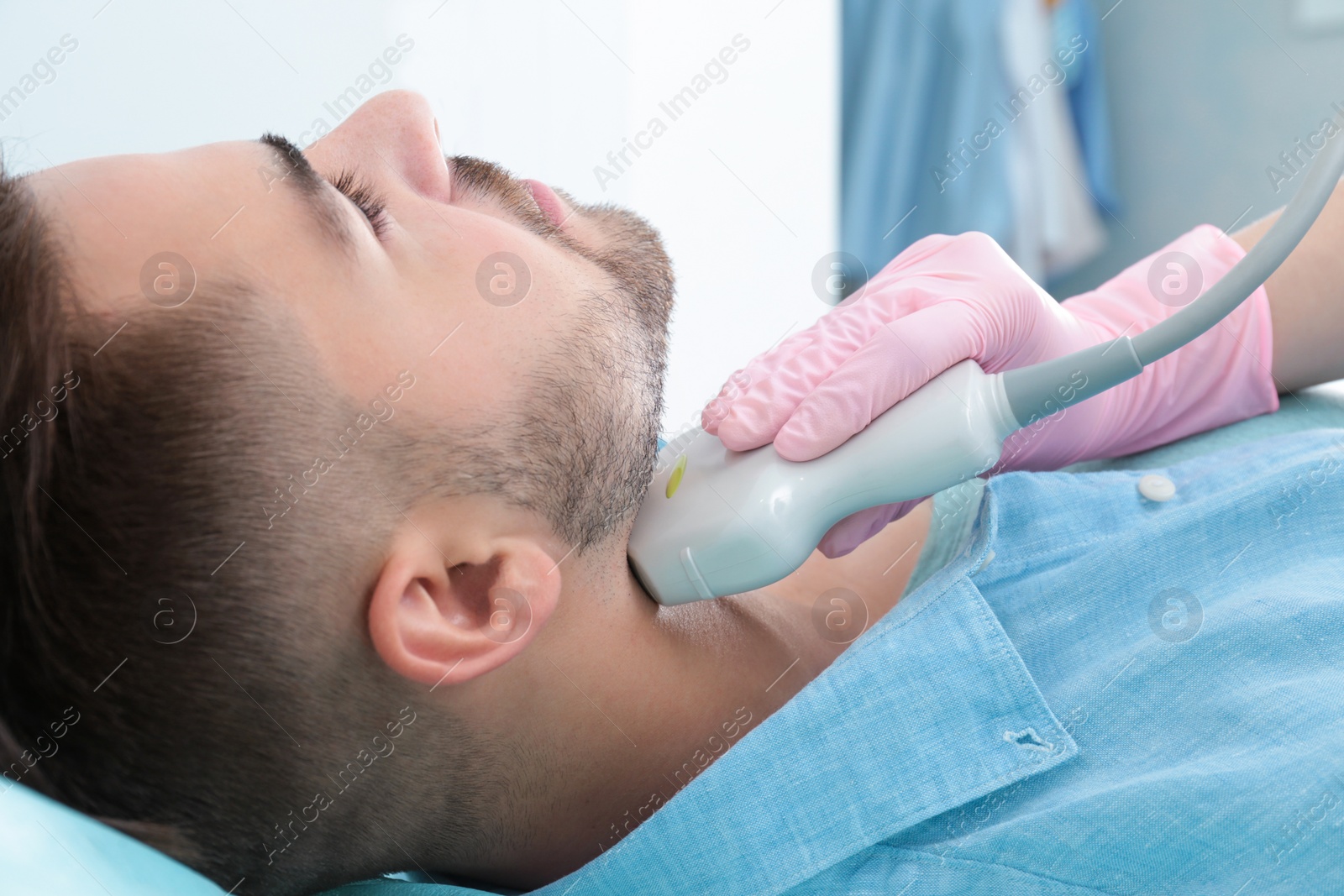 Photo of Doctor conducting ultrasound examination of patient's neck in clinic, closeup